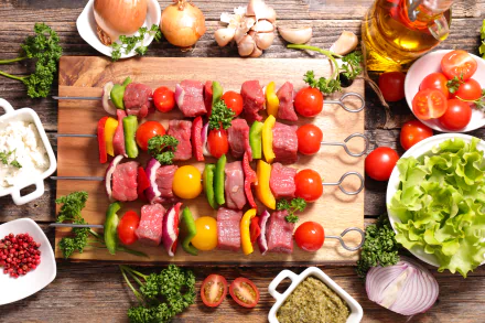 8K Ultra HD still-life PC desktop wallpaper and background of colorful barbecue skewers with tomatoes, bell peppers and meat on a wooden board, surrounded by lettuce and condiments.