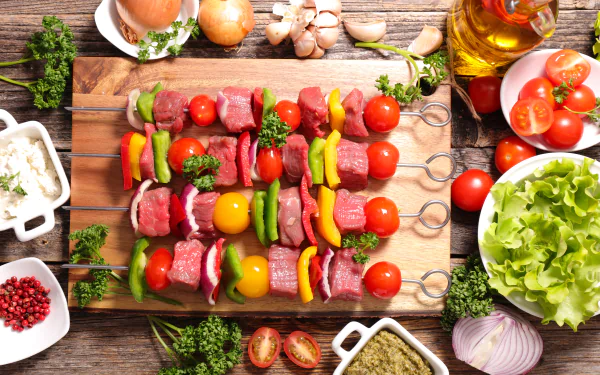 8K Ultra HD still-life PC desktop wallpaper and background of colorful barbecue skewers with tomatoes, bell peppers and meat on a wooden board, surrounded by lettuce and condiments.