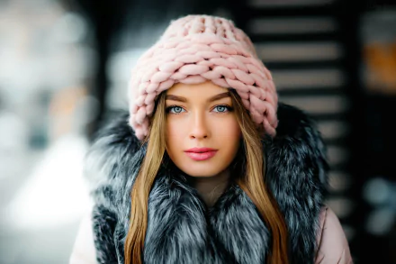 HD desktop wallpaper of a blonde model with blue eyes, pink knit hat and lipstick, wearing a fur-collared coat, shallow depth-of-field background.
