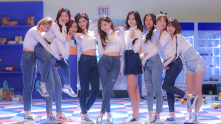 HD desktop wallpaper featuring the K-pop group TWICE. The members are dressed casually, posing together in a brightly lit room with a colorful floor background.