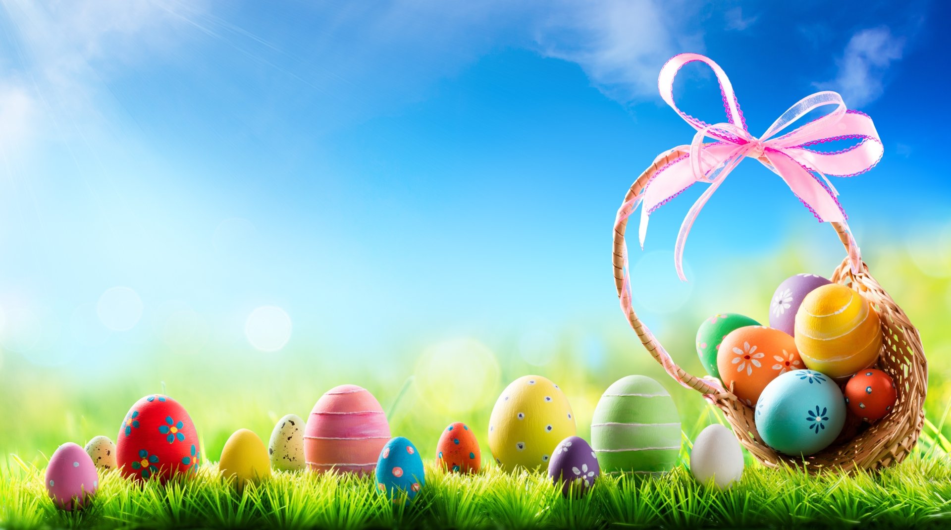 Colorful Easter eggs displayed on green grass under a bright blue sky, with a basket tied with a pink ribbon, captured in vivid 8K Ultra HD quality.