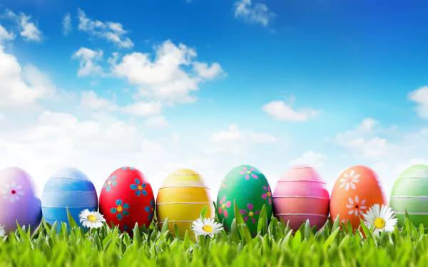 Vibrant Easter eggs in various colors rest on green grass under a bright blue sky with fluffy clouds, captured in stunning 8K Ultra HD for a festive holiday backdrop.