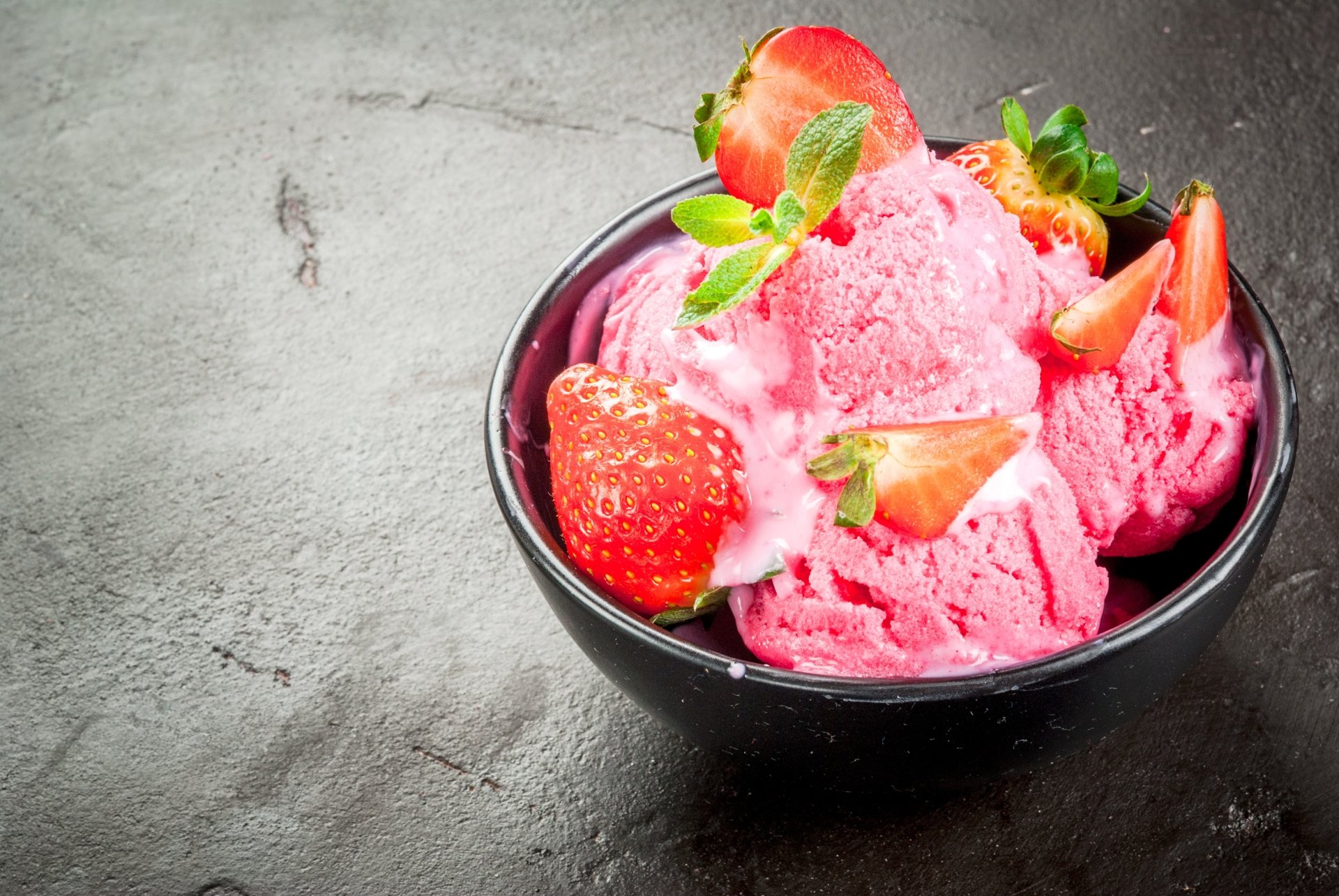 4K Ultra HD desktop wallpaper: bright pink strawberry ice cream scoops in a black bowl, topped with fresh strawberries and mint on a dark textured surface.