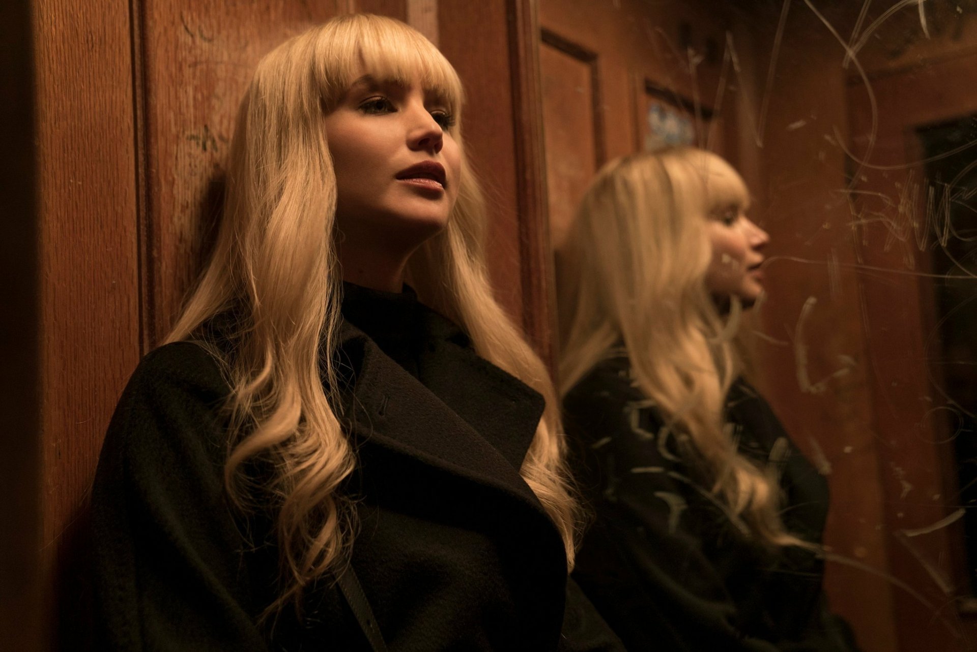 HD wallpaper featuring a scene from Red Sparrow with Jennifer Lawrence in a black coat, reflected in a mirror.