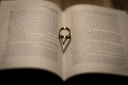 A man-made ring casting a heart-shaped shadow on the open pages of a book, symbolizing love; an HD PC desktop wallpaper and background.