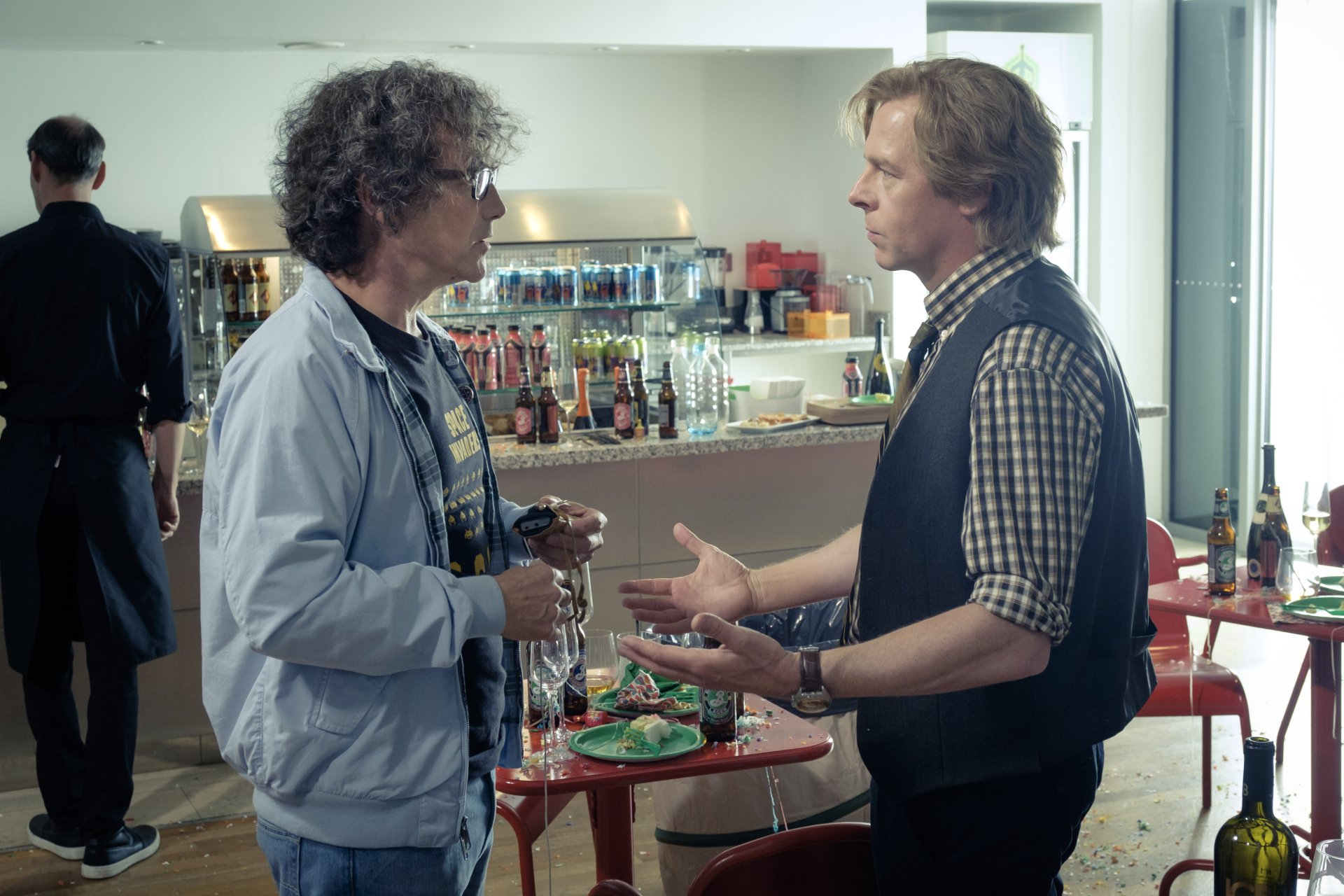Two men in casual clothes talk across a café-style table with drinks and snacks on a Ready Player One film set, rendered as a 4K Ultra HD PC desktop wallpaper.