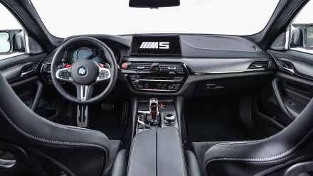 5K Ultra HD wallpaper: BMW M5 MotoGP Safety Car interior — cockpit view of BMW M5 with steering wheel, dashboard, center console and M5 branding.