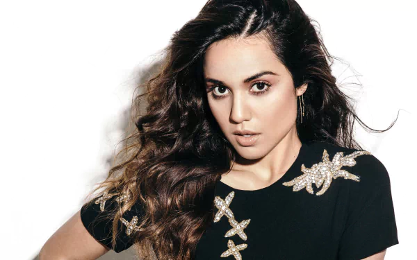 HD desktop wallpaper of American actress Summer Bishil with long brunette hair and brown eyes, wearing a black top adorned with decorative starfish patterns.