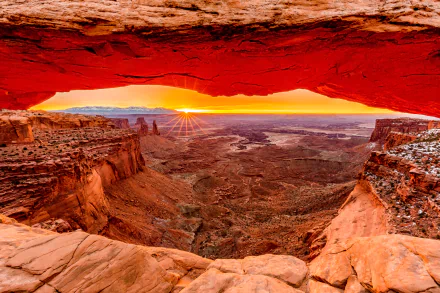 Sunrise view through Mesa Arch over vast desert landscape, captured in vibrant colors for a stunning 4K Ultra HD nature desktop wallpaper.