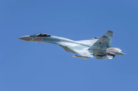 HD desktop wallpaper of a military Sukhoi Su-35 jet fighter soaring against a clear blue sky.