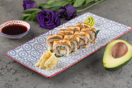 HD desktop wallpaper still life of seafood sushi rolls on patterned platter with pickled ginger, soy dipping sauce and halved avocado on concrete background with purple flowers.