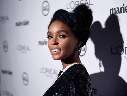 HD desktop wallpaper of Janelle Monae at an event, featuring her in profile with a smile against a logo backdrop.