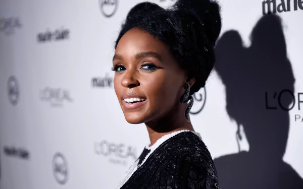 HD desktop wallpaper of Janelle Monae at an event, featuring her in profile with a smile against a logo backdrop.