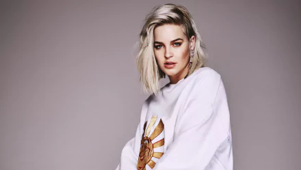 4K desktop wallpaper: blonde woman with blue eyes and statement earrings in a white sweatshirt, music-themed portrait against a soft neutral background.