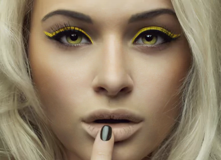 Close-up of a blonde woman's face with striking yellow eyes and bold yellow eyeliner, neutral lips — 4K Ultra HD PC desktop wallpaper/background.