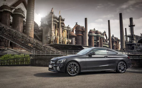 Silver Mercedes‑AMG C 43 coupe parked before a rusted industrial factory, dramatic lighting — 4K Ultra HD PC desktop wallpaper and background.