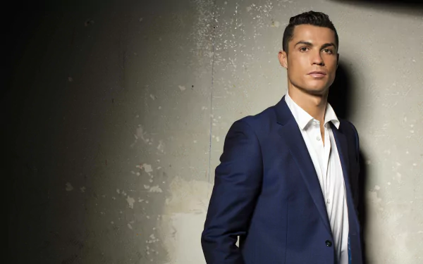 Portuguese soccer star Cristiano Ronaldo looks sharp in a suit against a textured wall. This HD desktop wallpaper captures a sophisticated side of the sports icon.