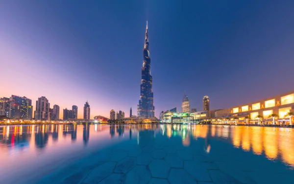 Nighttime view of Dubai’s Burj Khalifa and surrounding skyscrapers reflected in calm water, showcasing the vibrant cityscape of the United Arab Emirates.