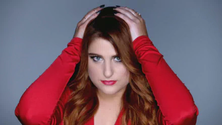 HD PC desktop wallpaper featuring Meghan Trainor in a red outfit against a gray background, highlighting her music career.