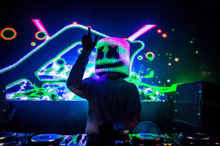 HD desktop wallpaper featuring DJ Marshmello performing with vibrant, neon lights in the background. The iconic Marshmello helmet glows under the dynamic light show, creating an energetic music atmosphere.