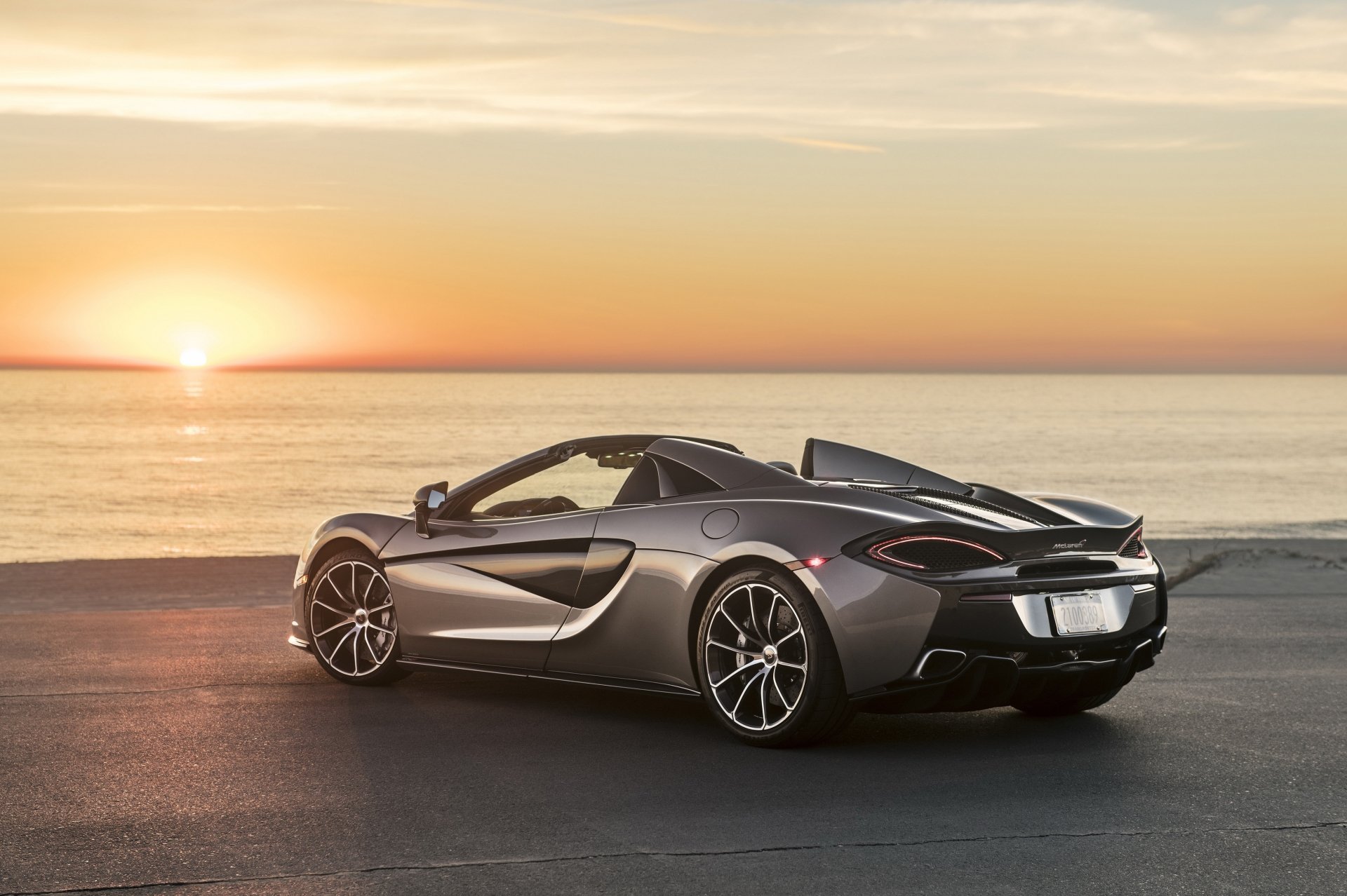 Silver McLaren 570S supercar parked near the ocean at sunset, captured in stunning 4K Ultra HD as a PC desktop wallpaper and background.
