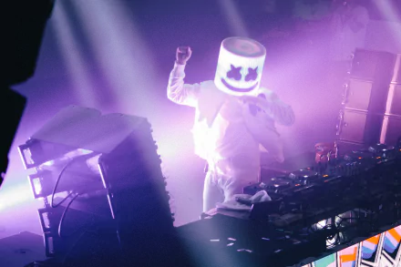 HD desktop wallpaper featuring Marshmello, the DJ, performing on stage with vibrant lights and equipment, creating a dynamic music atmosphere.