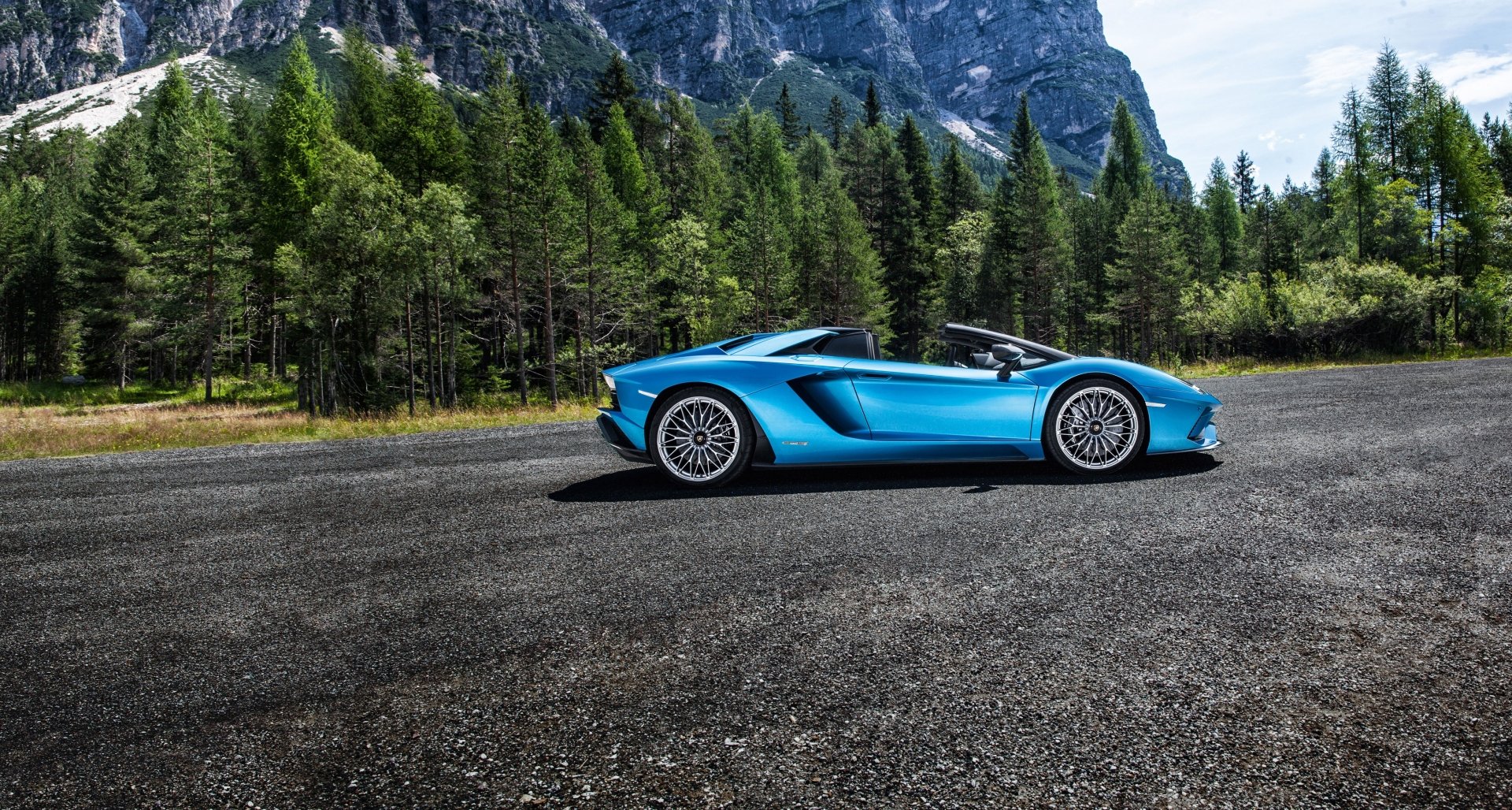 Blue Lamborghini Aventador S supercar (Lamborghini Aventador) — car/vehicle in side profile on a mountain road with forested peaks; 4K Ultra HD PC desktop wallpaper background.