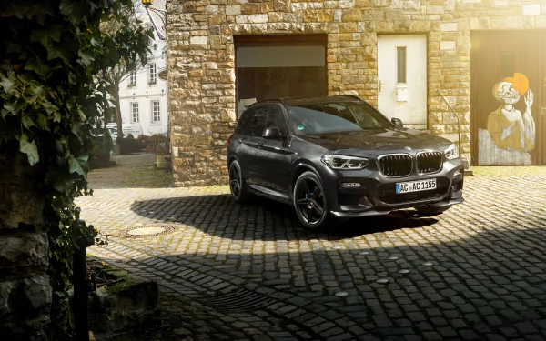 Black BMW X3 SUV parked on a cobblestone driveway in front of a stone building, captured in 4K Ultra HD.