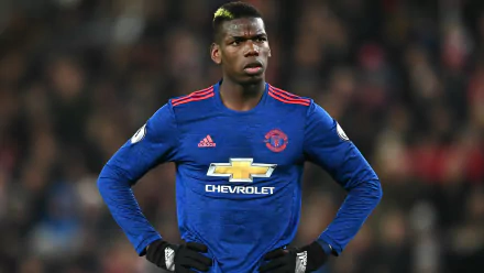 HD desktop wallpaper of the soccer player in a blue Manchester United jersey, hands on hips, on the field.