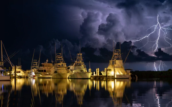 HD desktop wallpaper of a Florida marina at night showing yachts and a ship reflecting on calm water under a dramatic storm sky illuminated by lightning.