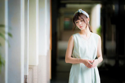 Brunette woman model in a pale dress poses in a softly blurred corridor; shallow depth of field, 4K Ultra HD PC desktop wallpaper background.