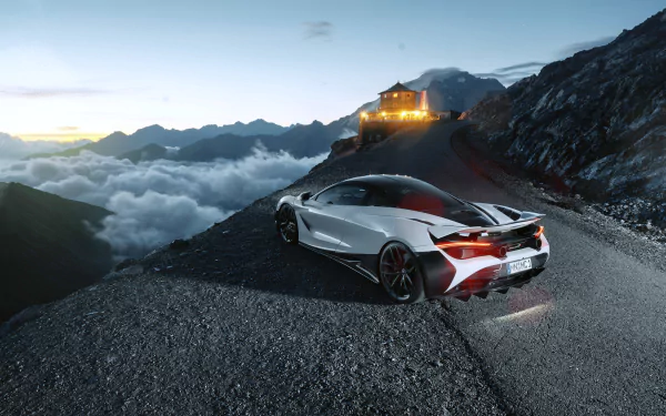 Silver McLaren 720S supercar parked on a mountain road at dusk, overlooking clouds and distant peaks, captured in stunning 4K Ultra HD detail.