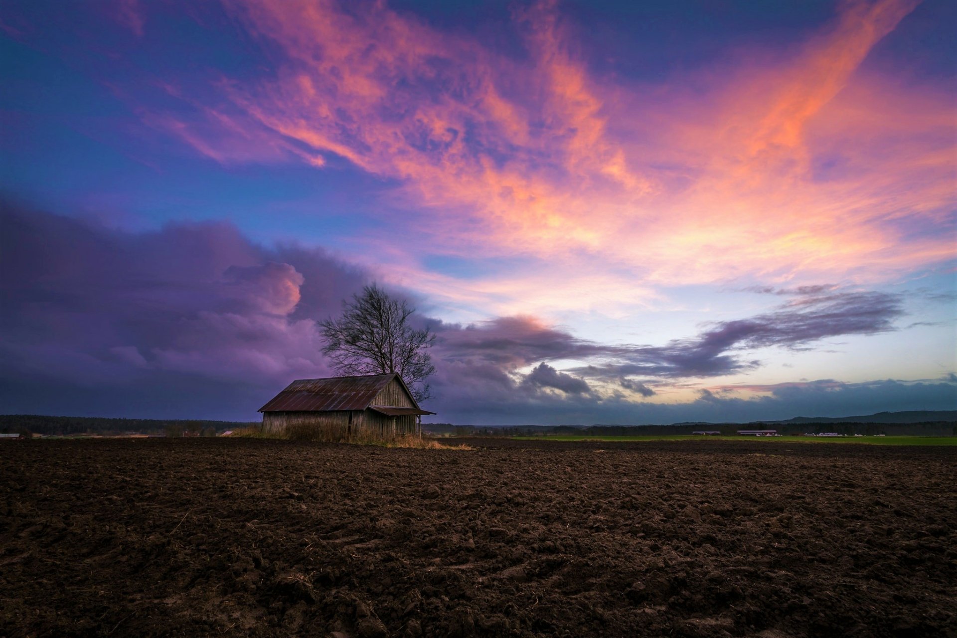A solitary shed stands in a vast field under a vibrant sunset sky, captured in stunning HD for a PC desktop wallpaper background.