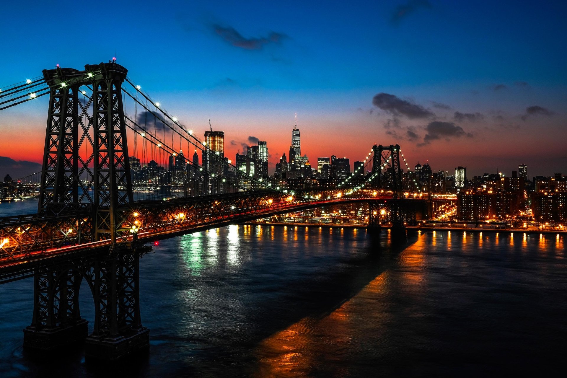 Night view of New York City skyline with the illuminated Williamsburg Bridge spanning the river, captured in HD for a vivid desktop wallpaper background.