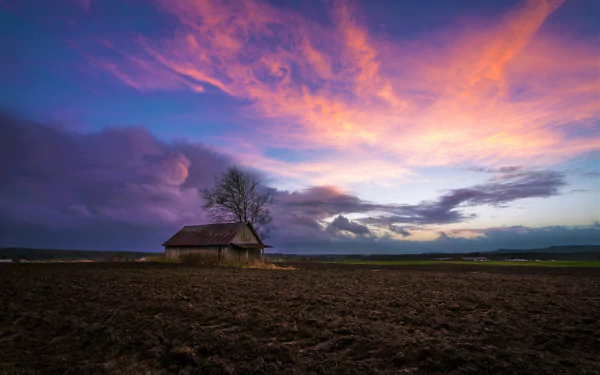 A solitary shed stands in a vast field under a vibrant sunset sky, captured in stunning HD for a PC desktop wallpaper background.
