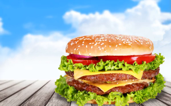 4K Ultra HD desktop wallpaper featuring a close-up of a juicy double cheeseburger with lettuce and tomato against a bright blue sky background.