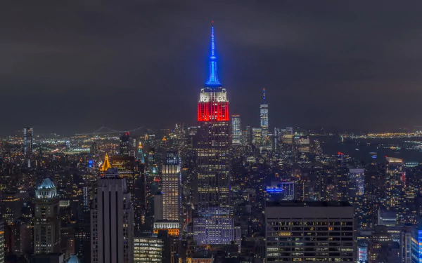 Nighttime view of New York City skyline featuring the illuminated Empire State Building among skyscrapers in this HD PC desktop wallpaper.