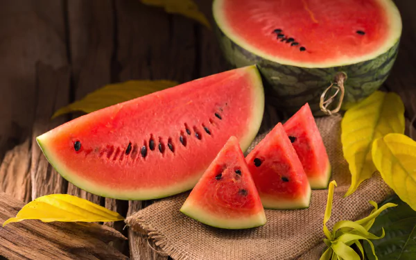 A vibrant still life of fresh watermelon slices and a halved watermelon set against a rustic wooden background, captured in 4K Ultra HD for a PC desktop wallpaper.