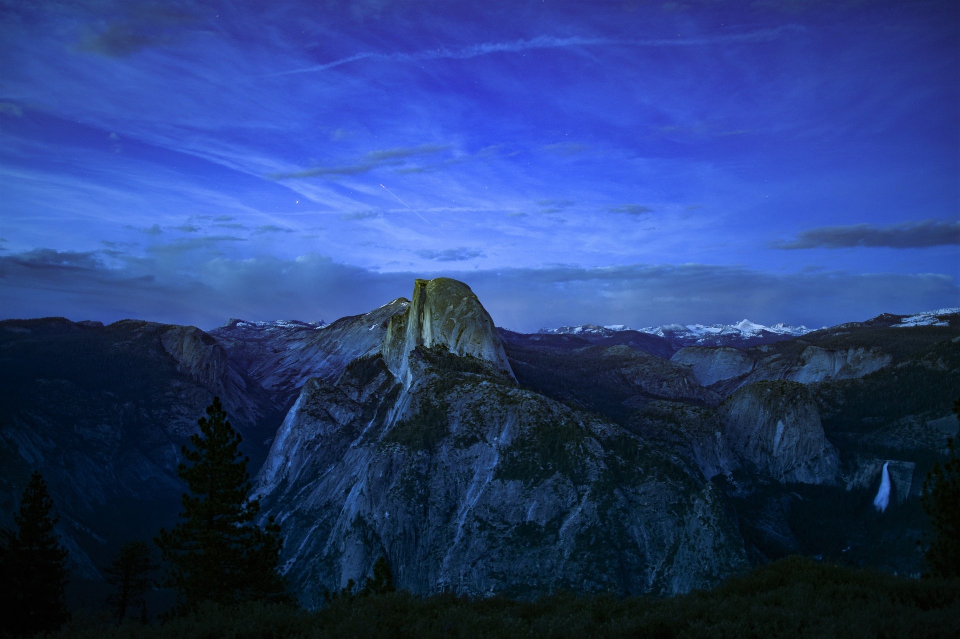 A serene dusk view of Yosemite National Park featuring a forested valley and rugged mountain peaks in 4K Ultra HD resolution.
