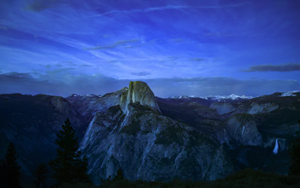 A serene dusk view of Yosemite National Park featuring a forested valley and rugged mountain peaks in 4K Ultra HD resolution.