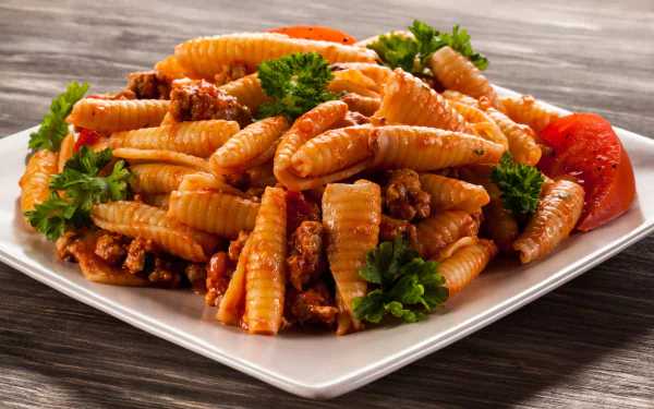 Close-up of pasta with meat sauce and parsley on a white plate, captured in vibrant detail for a 4K Ultra HD PC desktop wallpaper and background.