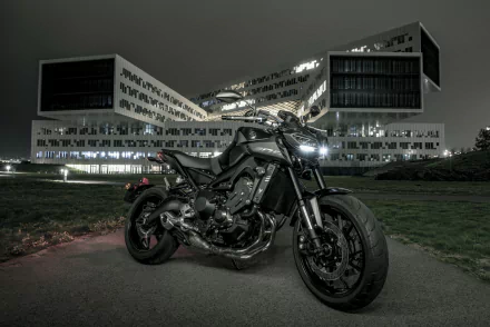 HD PC desktop wallpaper and background: black Yamaha MT-09 motorcycle vehicle parked at night on a path, headlights on, with an illuminated modern building behind it.