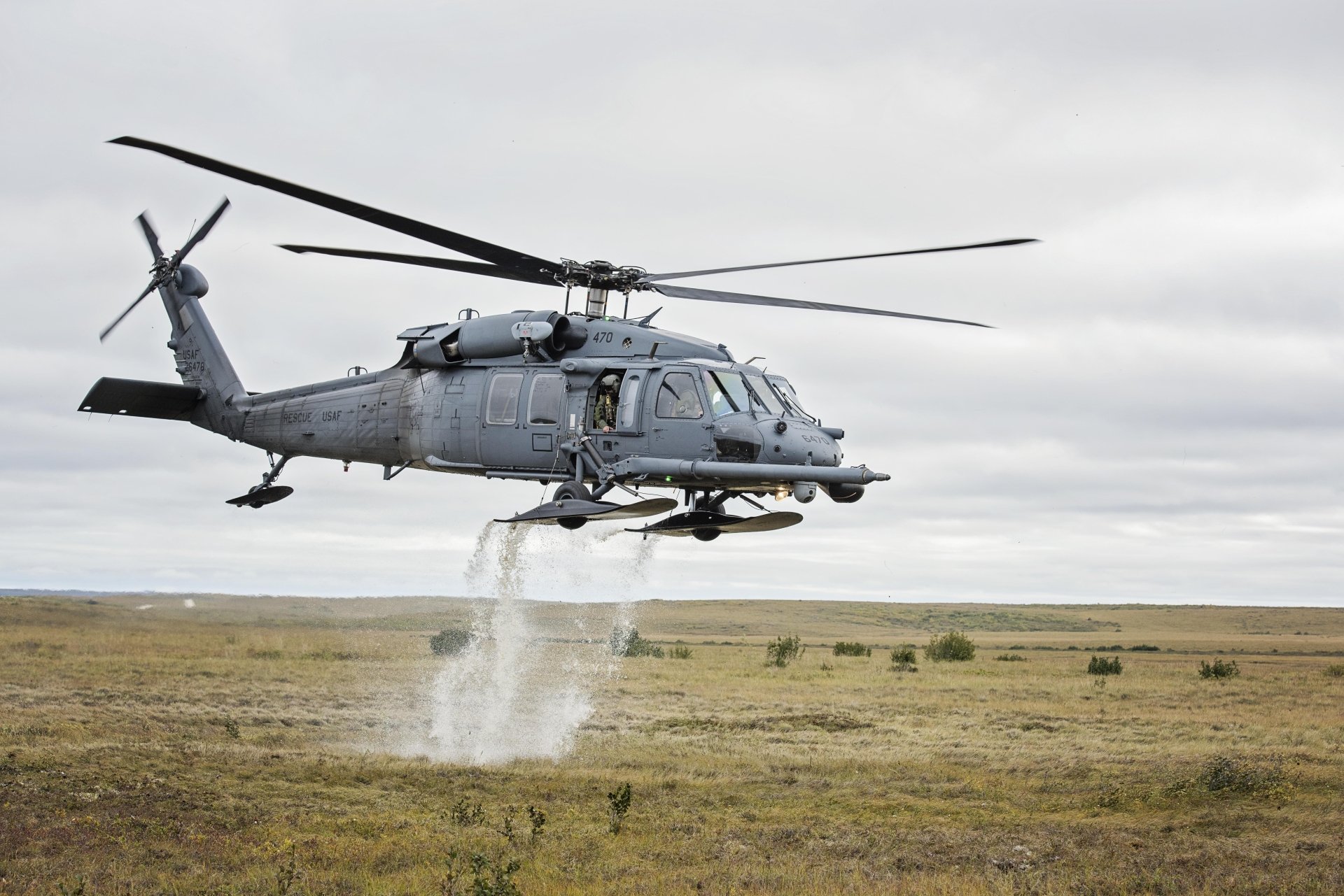 Military Sikorsky HH-60 Pave Hawk helicopter hovers low over open terrain, captured in 4K Ultra HD as a striking PC desktop wallpaper background.