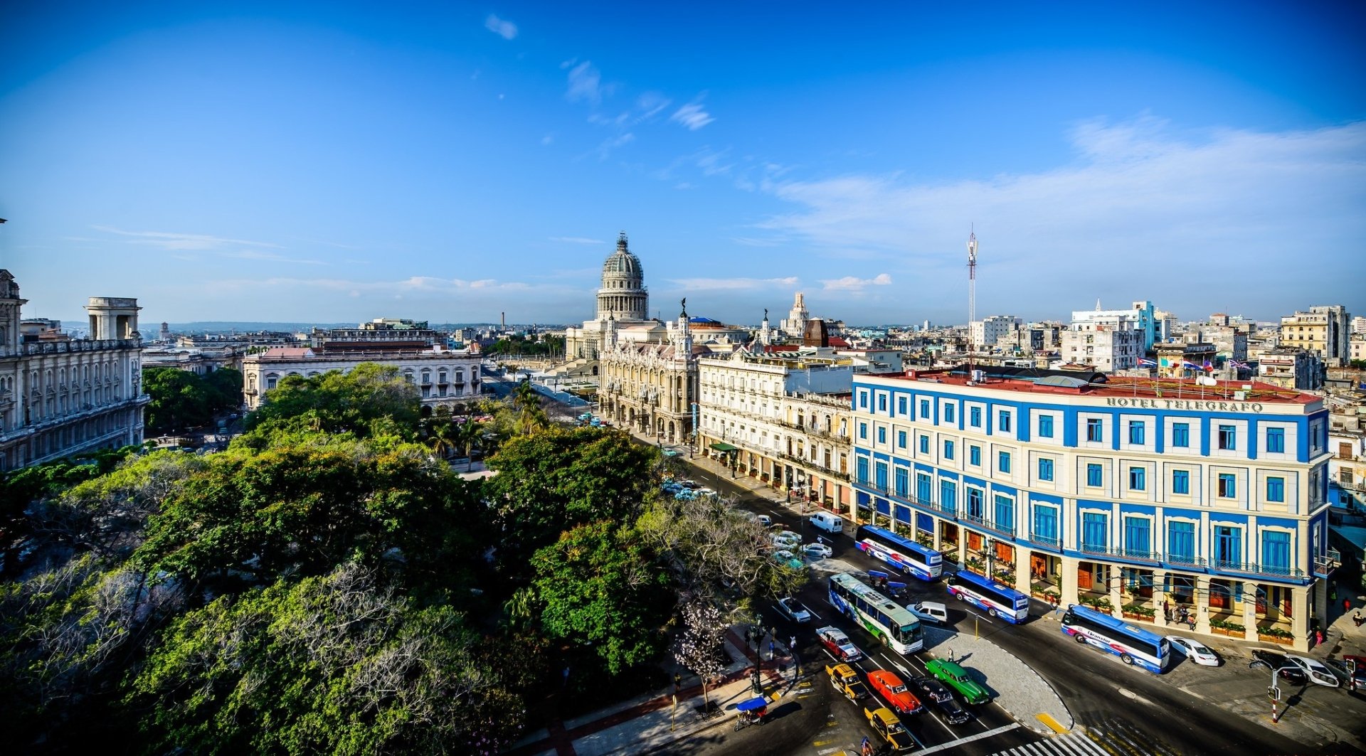 HD desktop wallpaper showcasing a vibrant man-made cityscape of Havana with classic architecture, lush greenery, and a bright blue sky.