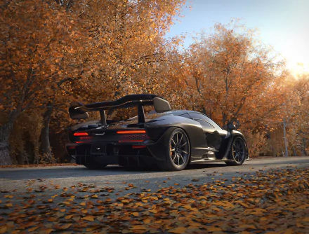 HD PC desktop wallpaper featuring a black McLaren Senna parked on a leaf-covered road surrounded by autumn trees.