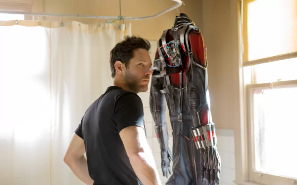 Paul Rudd as Ant-Man in a high-resolution 4K Ultra HD movie wallpaper, standing in a sunlit room next to the Ant-Man suit.