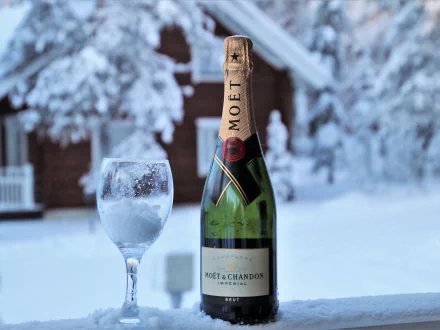 A 4K Ultra HD image of a Moët & Chandon champagne bottle and a frosted glass set against a snowy winter background, capturing a festive, elegant atmosphere.
