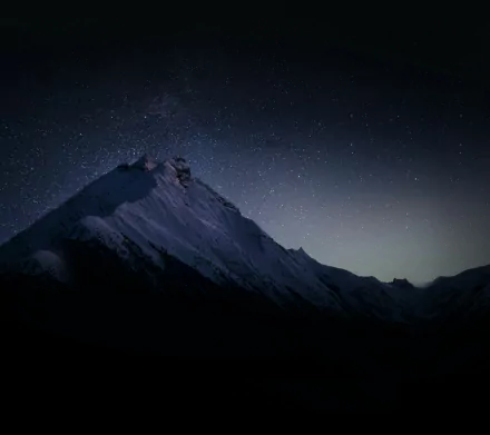 HD desktop wallpaper showing a serene mountain silhouette under a clear night sky filled with stars, capturing the beauty of nature at night.
