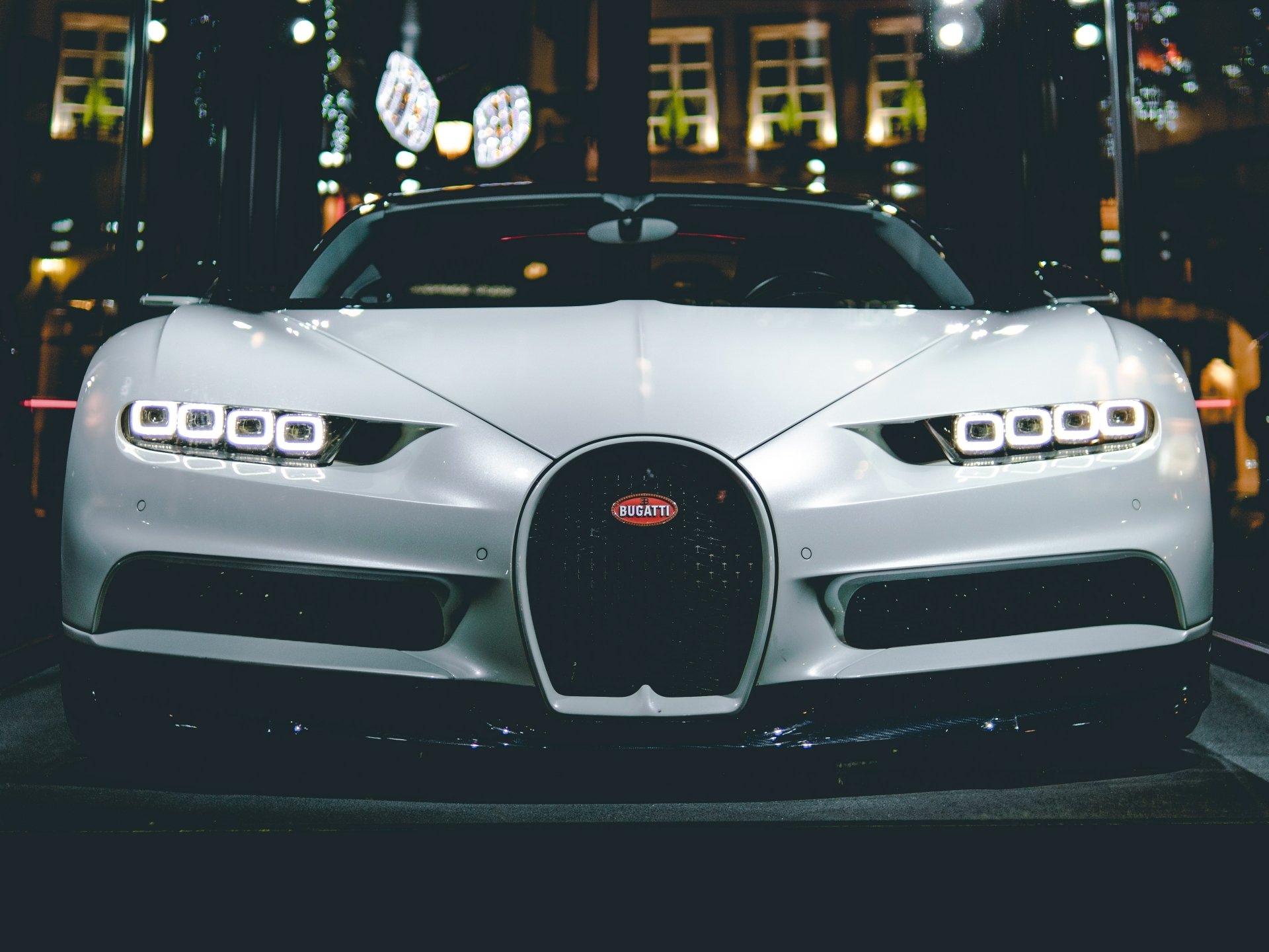 Front view of a white Bugatti Chiron at night, headlights and grille glowing against city lights — 4K Ultra HD PC desktop wallpaper and background.