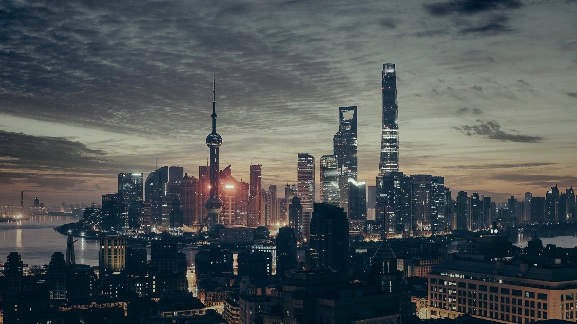 HD desktop wallpaper showcasing the man-made Oriental Pearl Tower and Shanghai skyline in China at dusk under a cloudy sky.